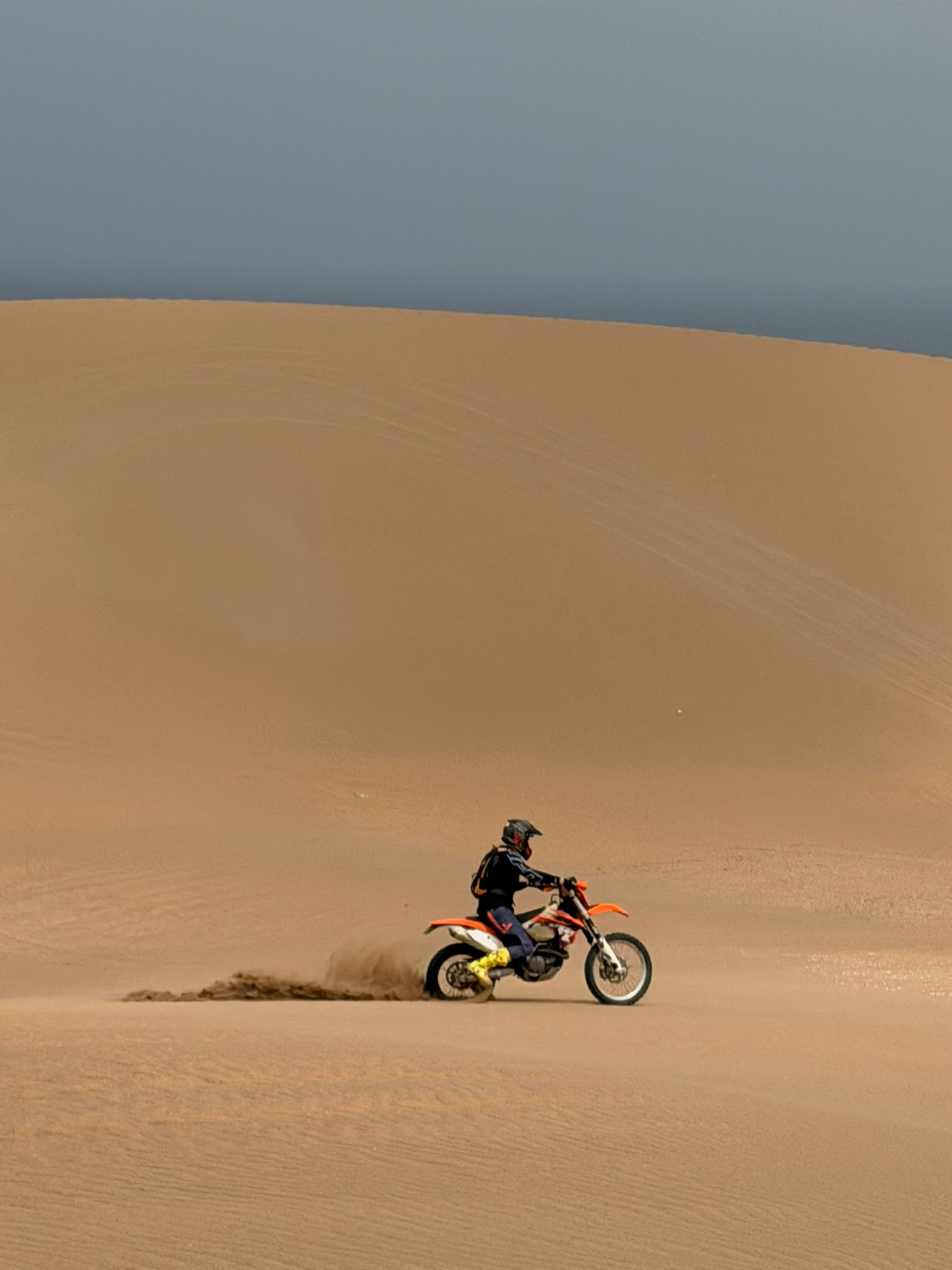 KTM 450 EXC-F lancée sur une crête de dune sous ciel bleu profond — arrière-pays d'Agadir